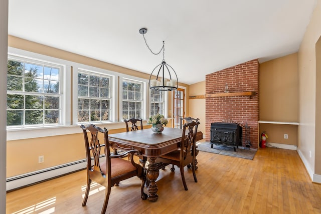 dining area with baseboard heating, a chandelier, light wood-type flooring, baseboards, and lofted ceiling