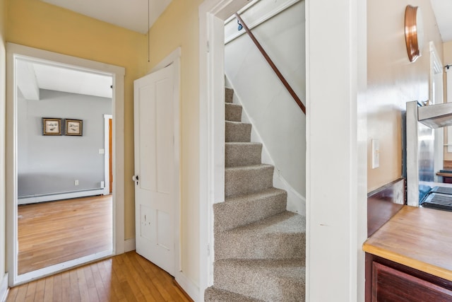 staircase featuring a baseboard heating unit and hardwood / wood-style flooring