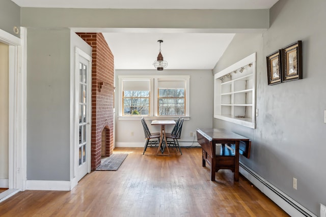 dining area featuring baseboards, vaulted ceiling, wood finished floors, and a baseboard radiator