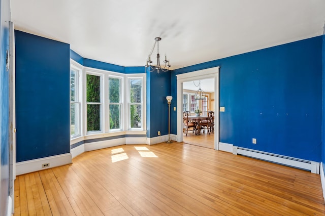 unfurnished room with hardwood / wood-style flooring, a baseboard radiator, baseboards, and a notable chandelier