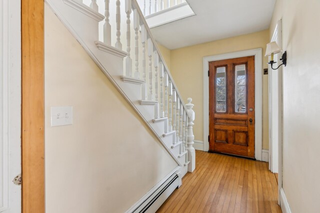 entrance foyer with light wood finished floors, baseboards, and stairway