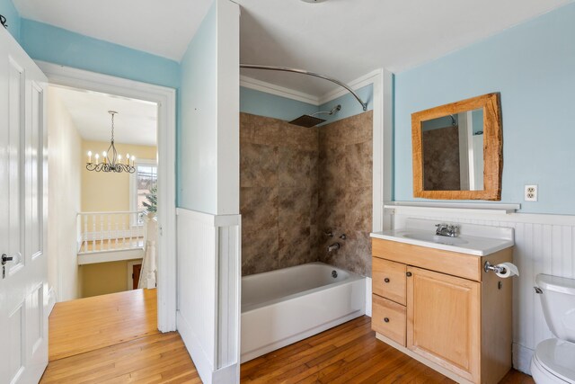 bathroom with a wainscoted wall, toilet, vanity, wood-type flooring, and shower / tub combination