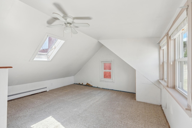 bonus room featuring a baseboard heating unit, lofted ceiling with skylight, light colored carpet, and ceiling fan