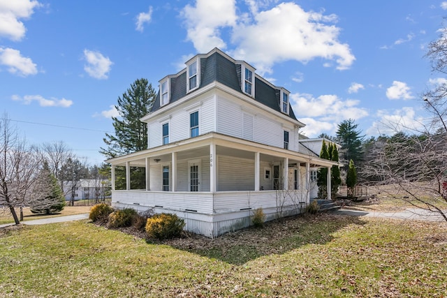 view of side of property featuring a yard, mansard roof, and covered porch