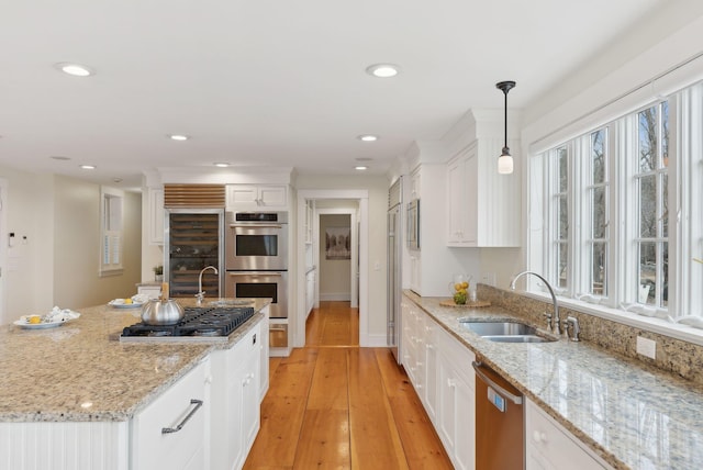 kitchen featuring white cabinets, a sink, light wood-style floors, and appliances with stainless steel finishes