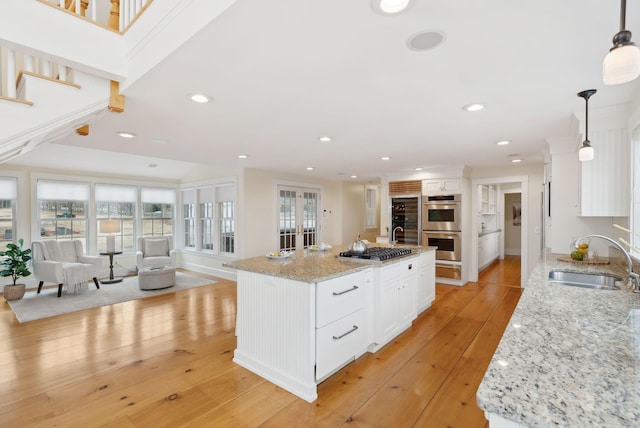 kitchen with appliances with stainless steel finishes, a sink, white cabinetry, and light wood-type flooring