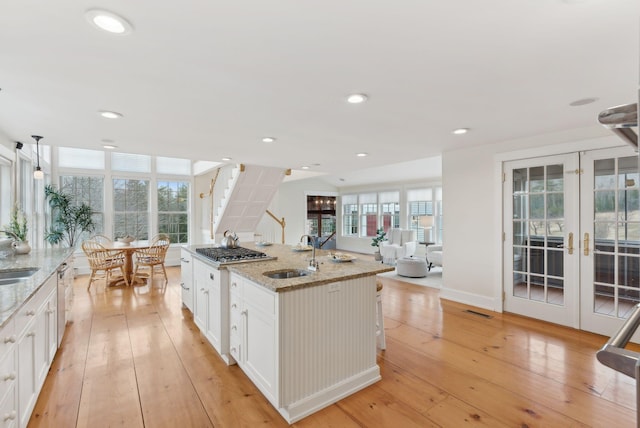 kitchen featuring visible vents, french doors, a sink, light wood-style flooring, and white cabinetry