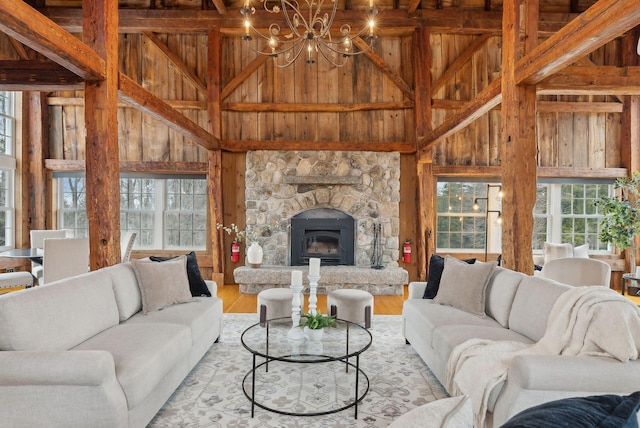 living room featuring wooden walls, wood finished floors, a healthy amount of sunlight, and high vaulted ceiling