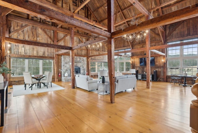 living room featuring wood-type flooring, beamed ceiling, a fireplace, high vaulted ceiling, and a notable chandelier