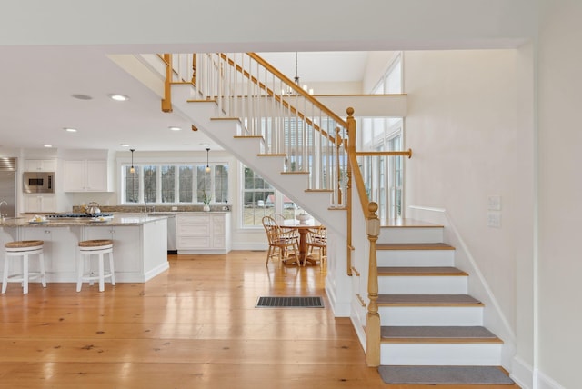 staircase featuring baseboards, wood finished floors, visible vents, and recessed lighting