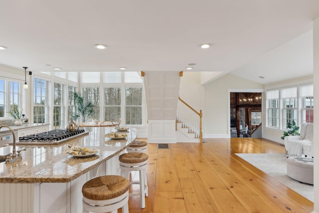 kitchen featuring light wood-style flooring, light stone countertops, pendant lighting, and a wealth of natural light