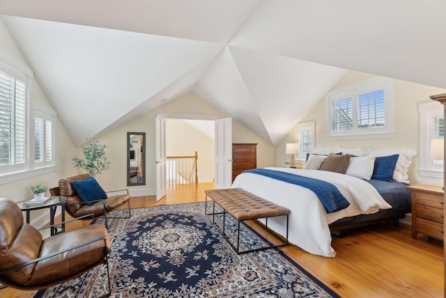 bedroom featuring light wood finished floors and lofted ceiling