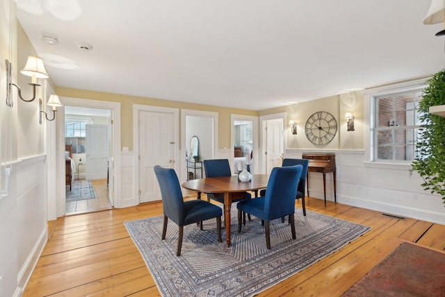 dining room featuring a wainscoted wall, visible vents, and light wood-style floors