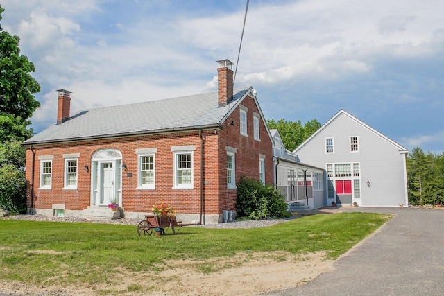 view of front of house with brick siding, a front lawn, and a chimney