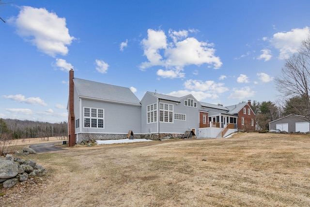 back of property with a lawn, a chimney, and an outbuilding