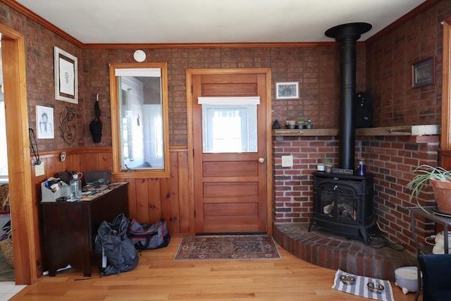 foyer entrance featuring wood finished floors, a wood stove, and crown molding