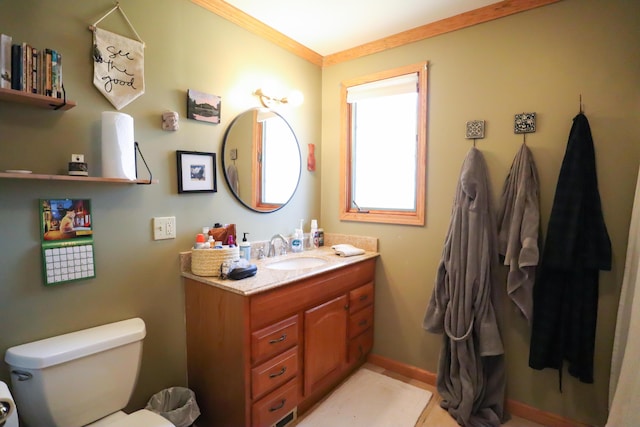 bathroom featuring crown molding, baseboards, vanity, and toilet