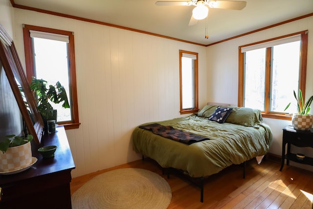 bedroom featuring ornamental molding, a ceiling fan, and light wood finished floors