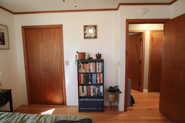 bedroom with wood finished floors, a closet, and crown molding