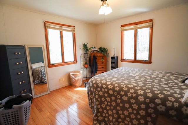 bedroom featuring baseboards, multiple windows, and light wood finished floors