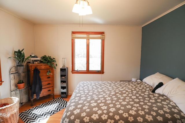 bedroom with wood finished floors and crown molding