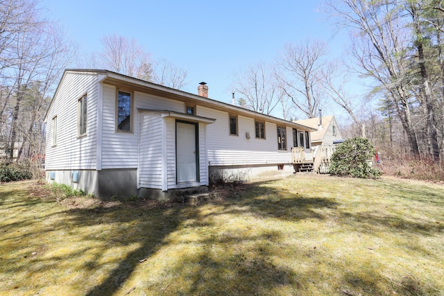 back of house featuring a yard, a chimney, and a deck