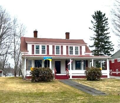 view of front of home featuring a chimney, a front yard, and covered porch