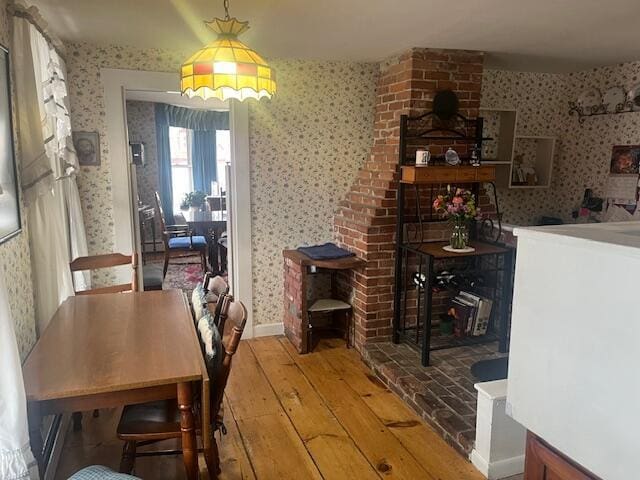 dining space featuring wallpapered walls and hardwood / wood-style floors