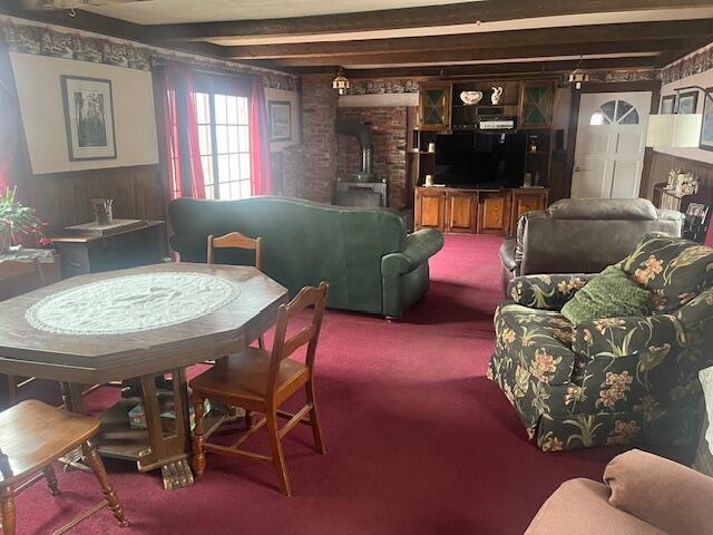carpeted living area featuring wood walls and a wood stove