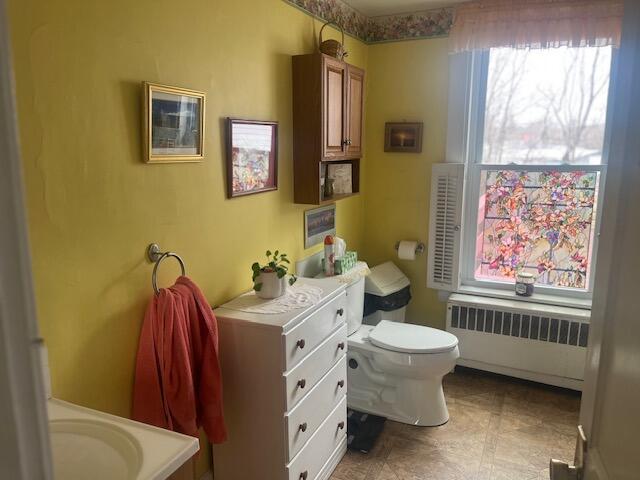 bathroom featuring radiator, a wealth of natural light, and toilet