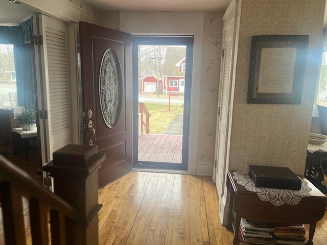 entrance foyer with wallpapered walls and light wood finished floors