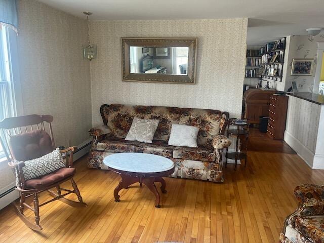 living area with a baseboard heating unit, wallpapered walls, and wood-type flooring