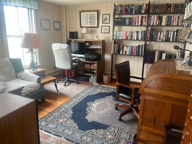 office with wallpapered walls and wood finished floors