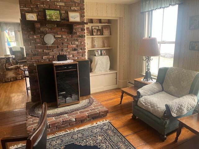 sitting room featuring wallpapered walls, wood finished floors, and a baseboard radiator