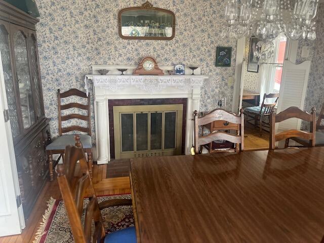 interior space featuring wallpapered walls, wood finished floors, and a glass covered fireplace