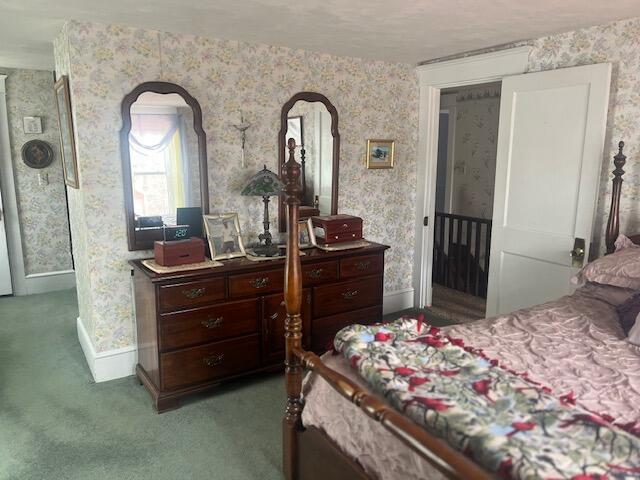 carpeted bedroom featuring wallpapered walls and baseboards