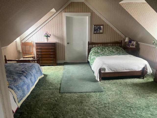 carpeted bedroom featuring vaulted ceiling and wooden walls