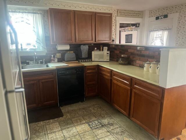 kitchen featuring light countertops, wallpapered walls, a sink, and white appliances