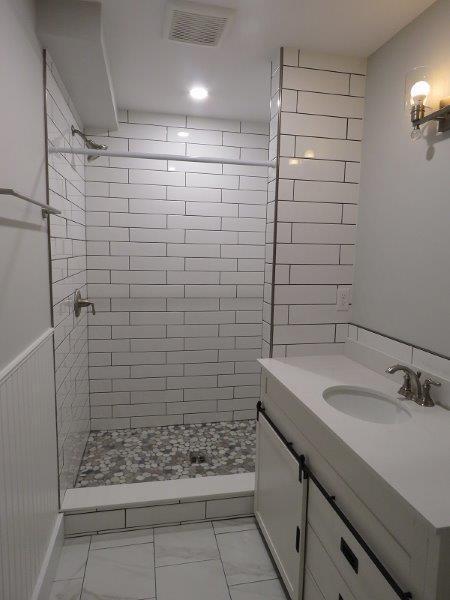 bathroom featuring visible vents, a stall shower, and vanity