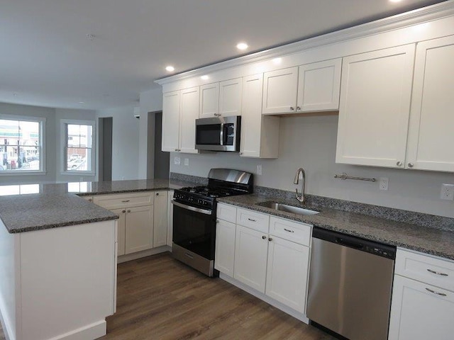 kitchen with white cabinets, a sink, appliances with stainless steel finishes, a peninsula, and recessed lighting