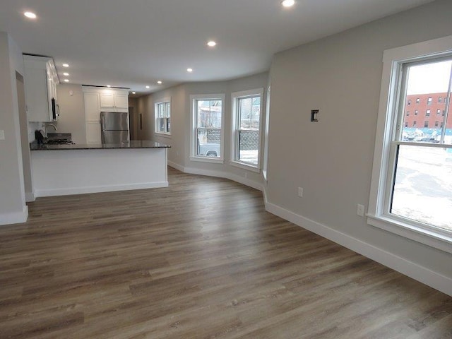 unfurnished living room with wood finished floors, baseboards, and recessed lighting