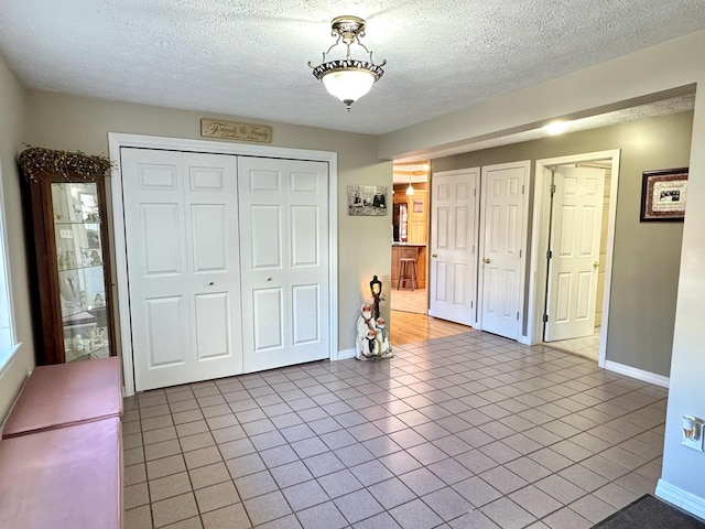 182 E Main St, Fort Kent, ME 04743 - unfurnished bedroom featuring a textured ceiling, tile patterned floors, baseboards, and a closet