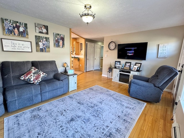 182 E Main St, Fort Kent, ME 04743 - living area with a baseboard heating unit, light wood-style flooring, a textured ceiling, and baseboards
