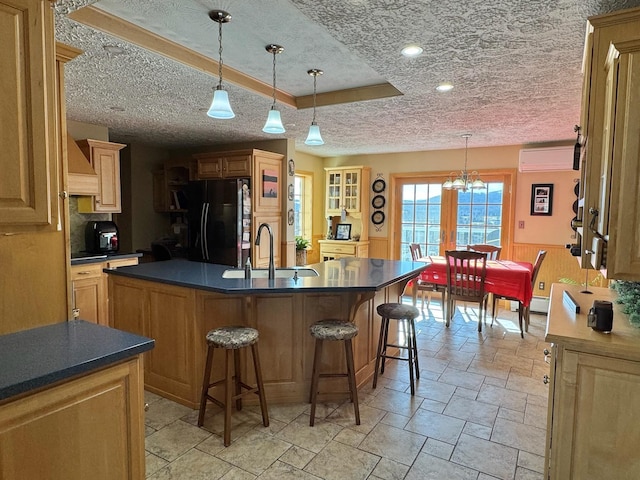 182 E Main St, Fort Kent, ME 04743 - kitchen with freestanding refrigerator, an AC wall unit, a textured ceiling, a kitchen bar, and an island with sink