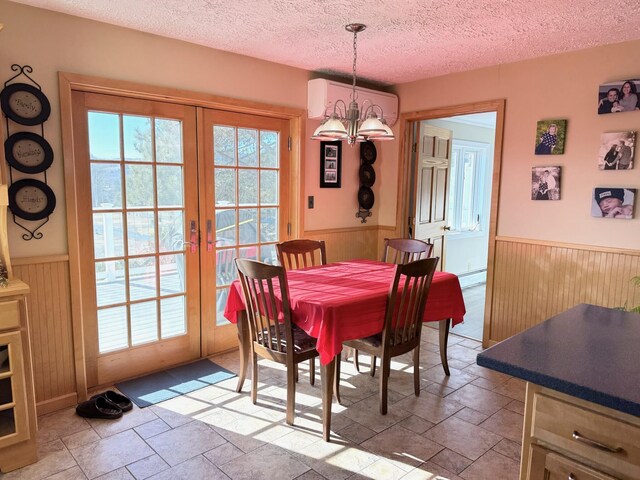 182 E Main St, Fort Kent, ME 04743 - dining room with a wainscoted wall, stone tile flooring, a chandelier, french doors, and wood walls