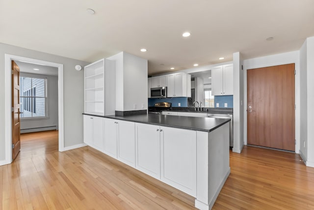6 Merritt House Rd Unit 20, Harpswell, ME 04066 - kitchen featuring appliances with stainless steel finishes, a baseboard radiator, a peninsula, dark countertops, and plenty of natural light