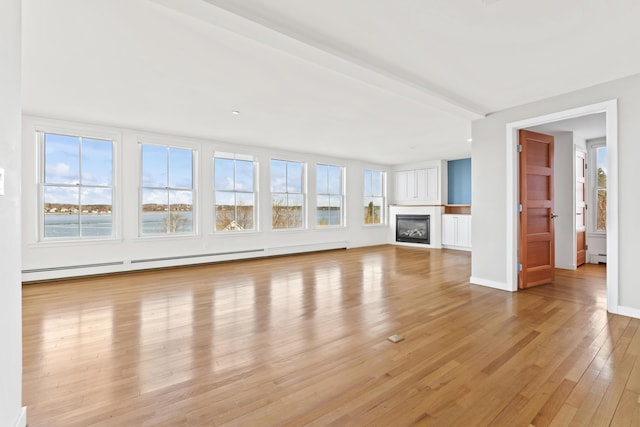 6 Merritt House Rd Unit 20, Harpswell, ME 04066 - unfurnished living room with healthy amount of natural light, light wood-style flooring, a baseboard radiator, and a glass covered fireplace