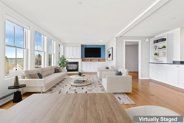 6 Merritt House Rd Unit 20, Harpswell, ME 04066 - living area with a glass covered fireplace, light wood-style floors, and a baseboard heating unit