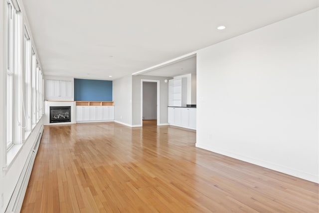 6 Merritt House Rd Unit 20, Harpswell, ME 04066 - unfurnished living room featuring light wood-style flooring, a large fireplace, baseboard heating, baseboards, and recessed lighting