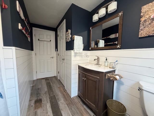 54 Black Smith Rd Unit 13, Wells, ME 04090 - bathroom featuring vanity, wood finished floors, toilet, and a wainscoted wall